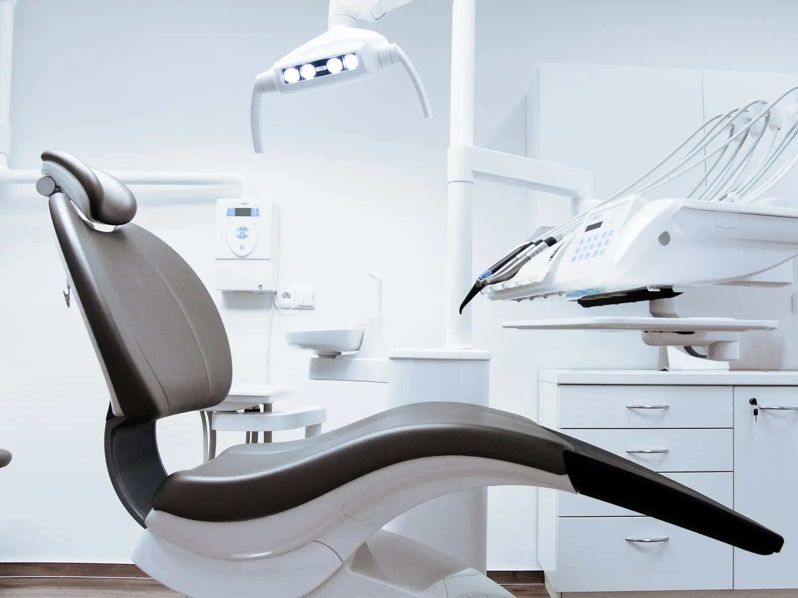 Consultório odontológico claro, com cadeira moderna e equipamentos brancos